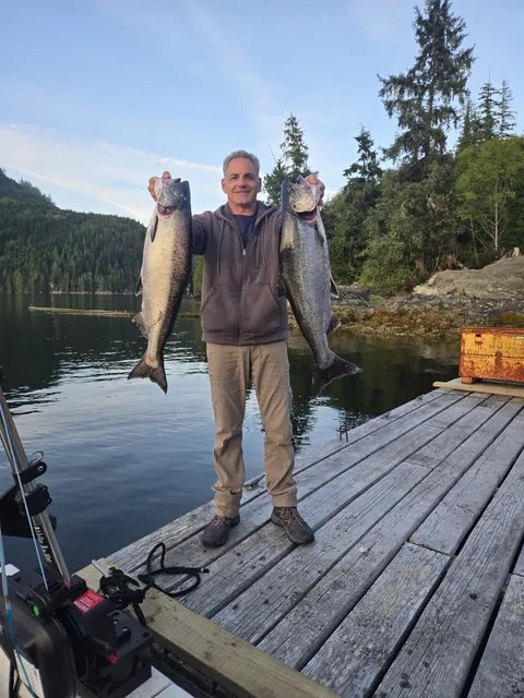 Angler holding two salmon on a coastal dock
